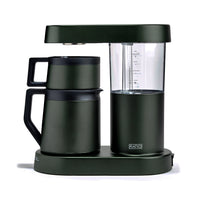 A dark forest green coffee maker with a matching carafe and base, featuring a clear water reservoir and a small visible RATIO logo on the front, set against a plain white background.